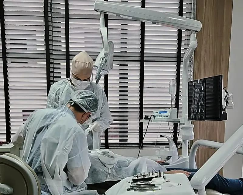 Cirurgia de implante na sala do consultório, com a equipe paramentada